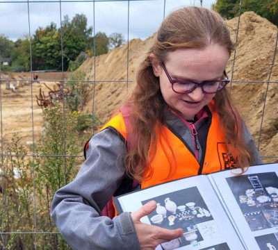 Archeoloog Ester met een boek vol plaatjes van archeologische vondsten