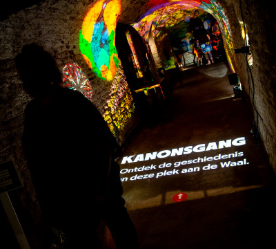 De donkere kanonsgang van Museum De Bastei met kleurrijke lichtprojecties.