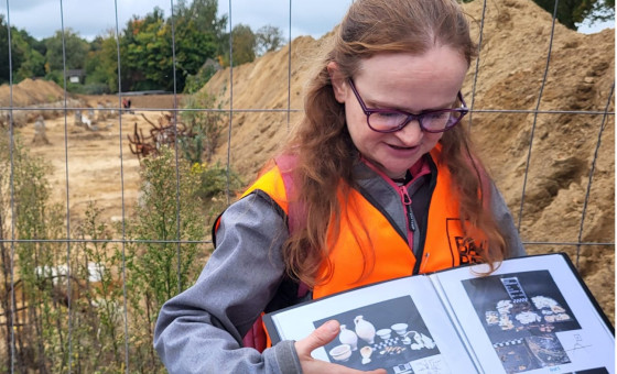Archeoloog Ester met een boek vol plaatjes van archeologische vondsten