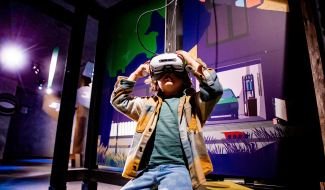 Jonge bezoeker probeert de VR in de tentoonstelling De Grote Reis van Klein Plastic. 