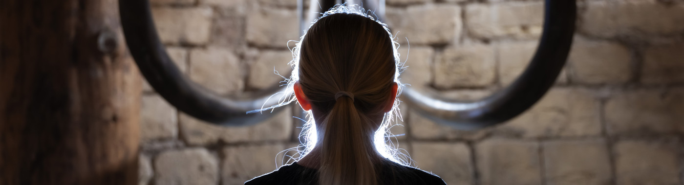 Jonge bezoeker op de rug gezien die recht tegenover de mammoetschedel zit.