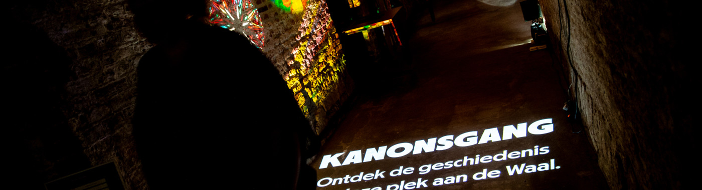 De donkere kanonsgang van Museum De Bastei met kleurrijke lichtprojecties.