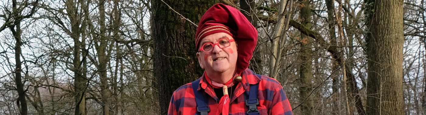Kabouter Fluitekruid zittend voor een boom in het bos. 