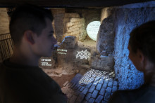 Twee mensen op voorgrond met de gelaagde archeologische vondsten in het museum.