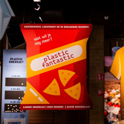 Grote informatiepanelen in de vorm van plastic producten zoals een rode zak chips op de voorgrond.