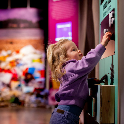 Jonge bezoeker speelt met interactieve presentatie door magneten te plaatsen.